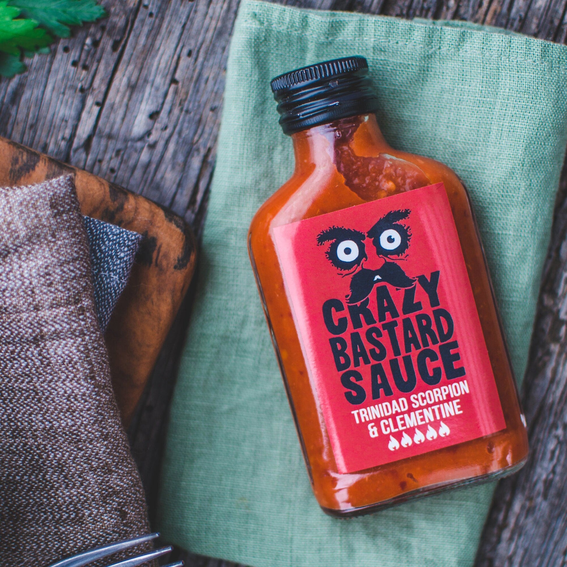 Intensely spicy Trinidad Scorpion pepper and clementine hot chilli sauce, handcrafted in the UK, ideal for adding a fruity kick to grilled meats and seafood.